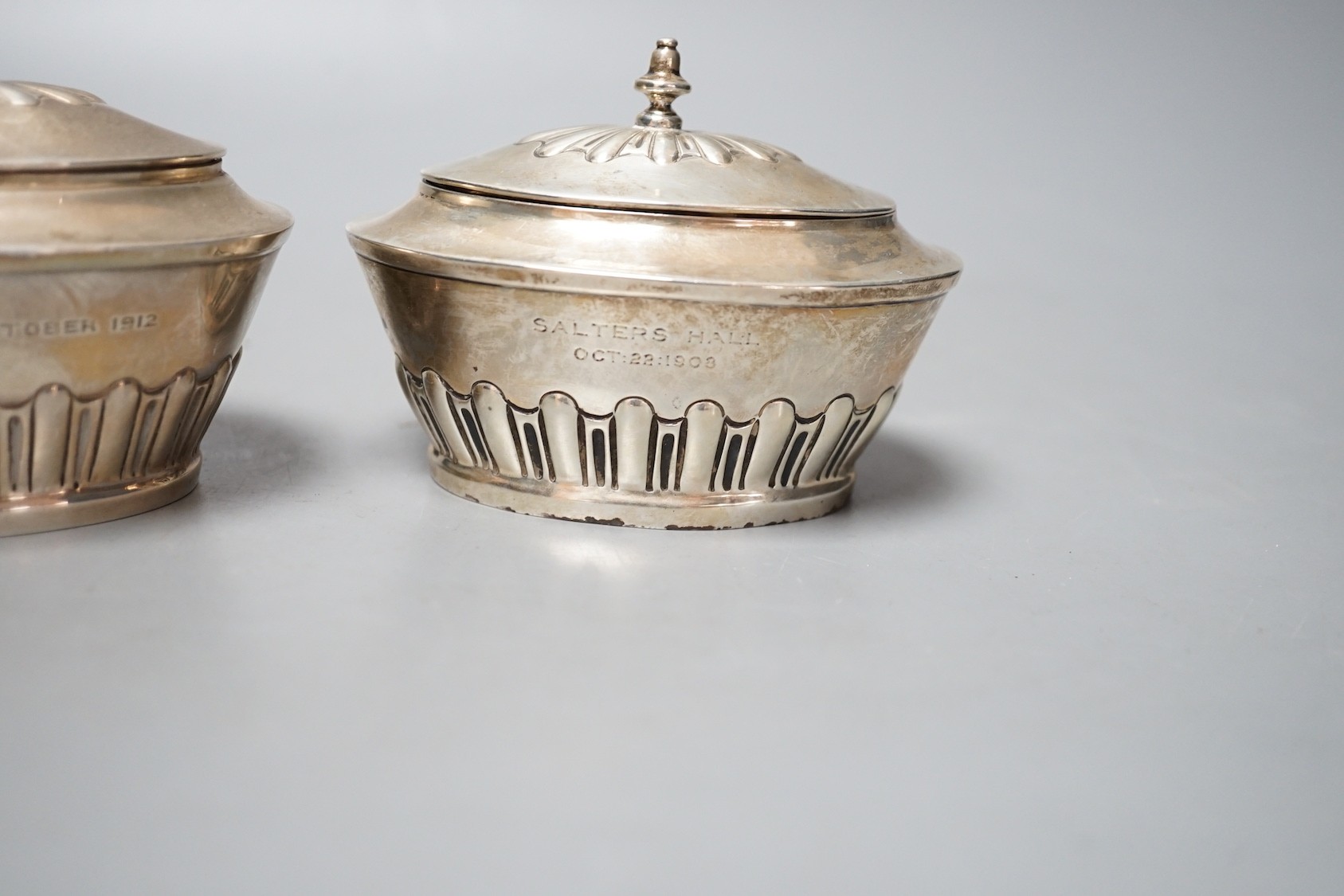 A matched pair of early 20th century silver oval tea caddies, London, 1908 & 191, width 10.5cm and two early 20th century silver leaf caddy spoons, one Britannia standard.